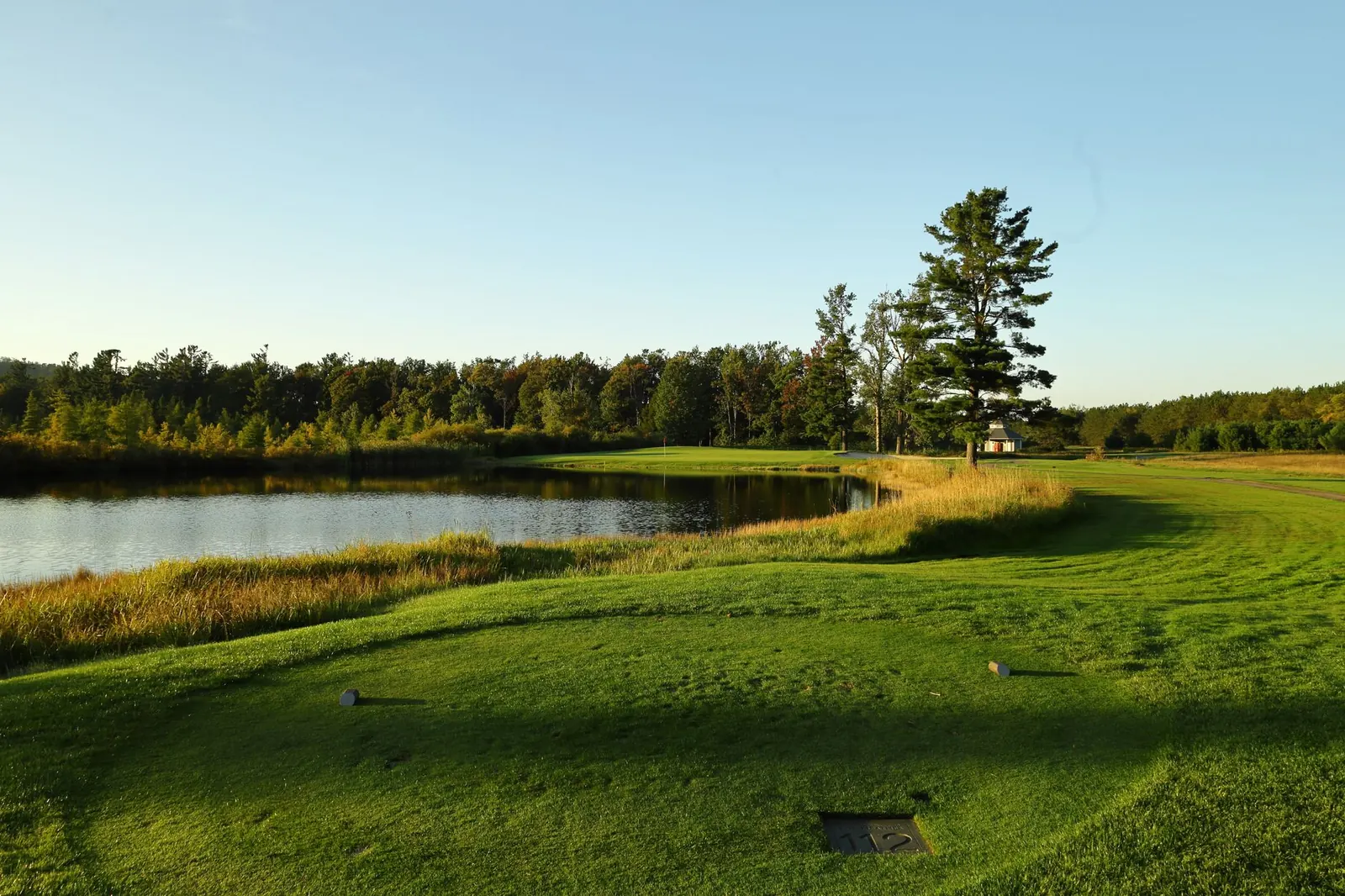 A golf course tee area beside water in early morning light